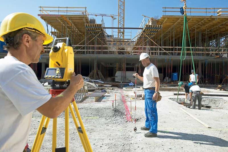 Геодезист работает с электронным тахеометром на строительной площадке